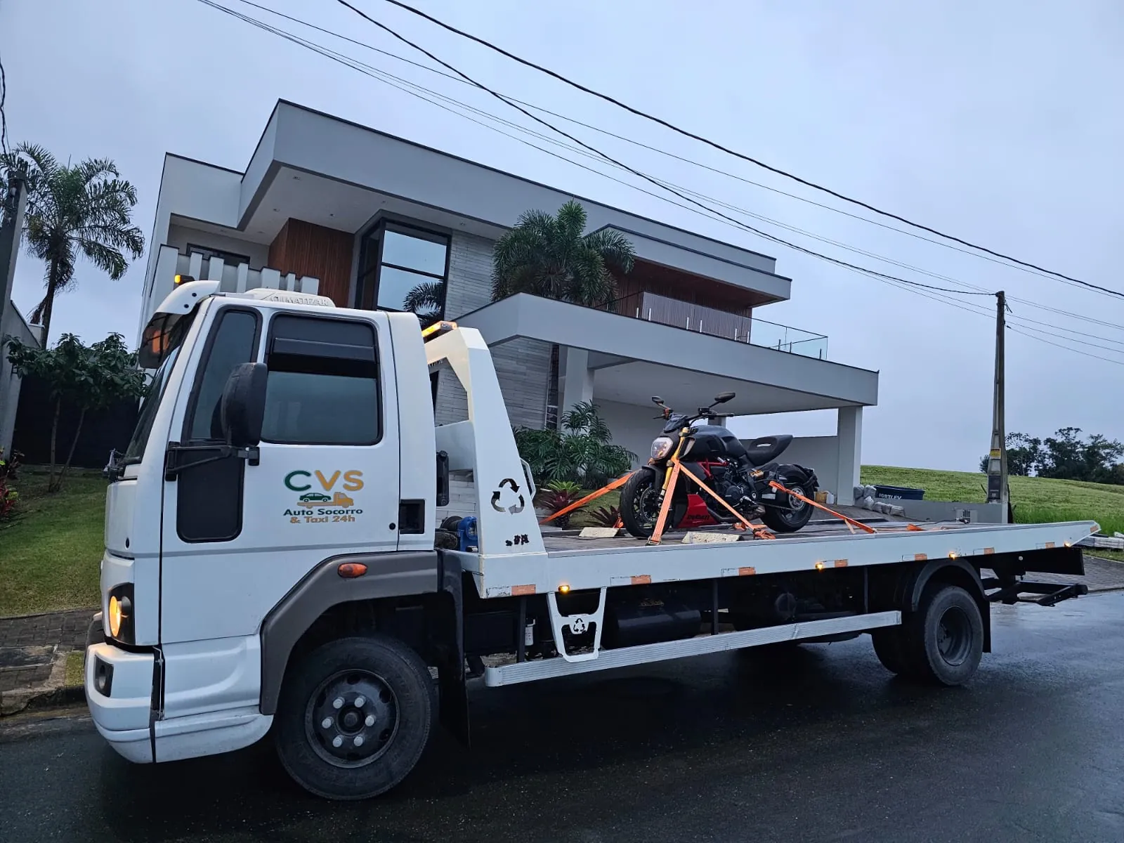 Caminhão da CVS visto de lado, com uma motocicleta acomodada na plataforma.